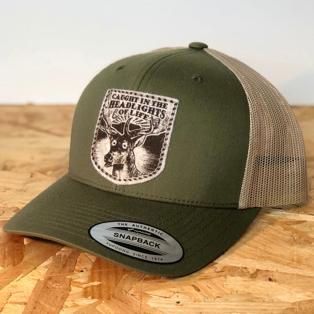 Caught in the headlights of life green/khaki two tone snapback retro trucker cap, screen printed on wool felt patch with deer graphic and text  